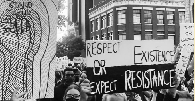A black-and-white photo of a protest shows people holding signs, including one that reads Respect existence or expect resistance and another that says Stand together for educational equity. Buildings are visible in the background.