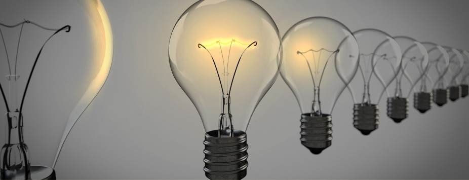 A row of clear incandescent light bulbs stands in a line, with only one bulb illuminated among several unlit bulbs, symbolizing unique ideas that can light pathways for the school community.