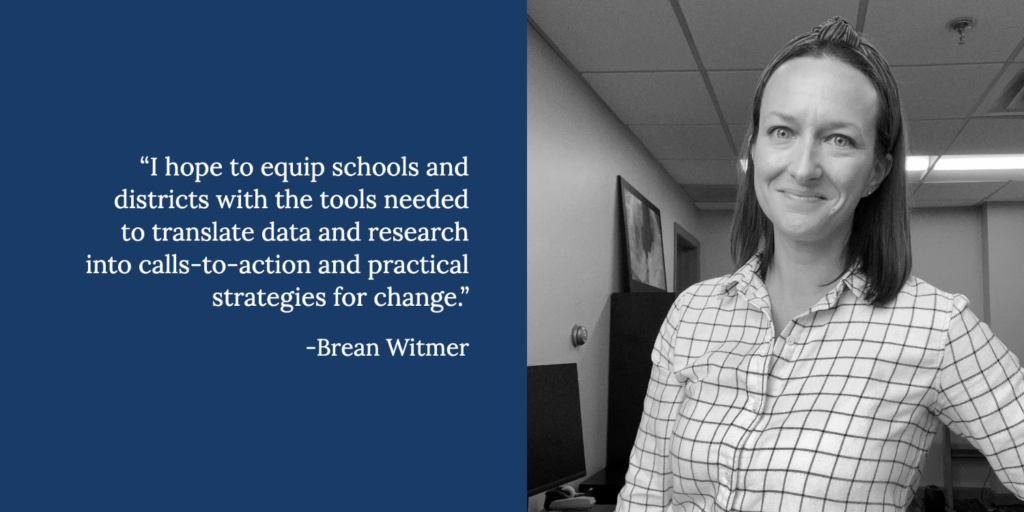 A woman in a plaid shirt stands smiling in an office. Next to her is a quote from Brean Witmer, Director of Research, about helping schools use data and research for practical change, featured in an interview.