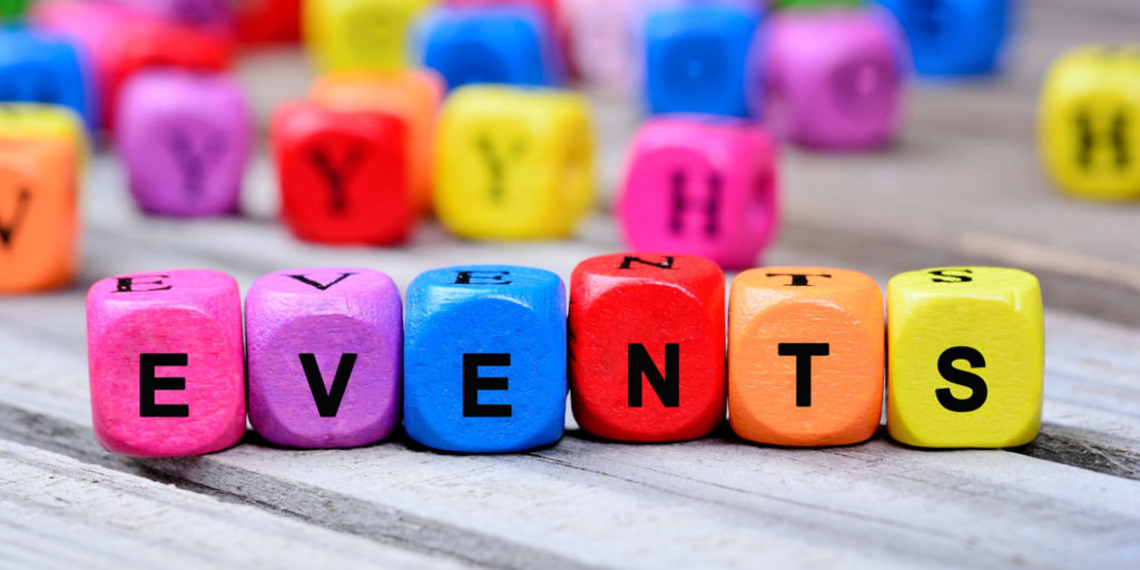 Colorful wooden blocks with letters spell out the word EVENTS on a wooden surface, hinting at upcoming events and learning opportunities, with other blurred letter blocks in the background.