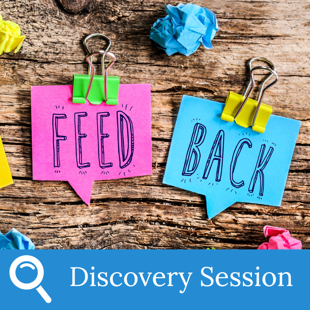 Two paper notes on a wooden surface, one pink labeled FEED and one blue labeled BACK, each held with a binder clip. Crumpled paper balls and a Discovery Session banner suggest grading strategies to boost student engagement.