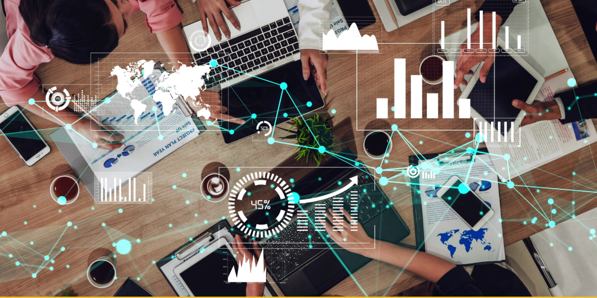 Top-down view of people working at a table with laptops, tablets, and documents, with digital data graphics overlays—charts, world map, and network connections—symbolizing teamwork leveraging data for equitable student outcomes.