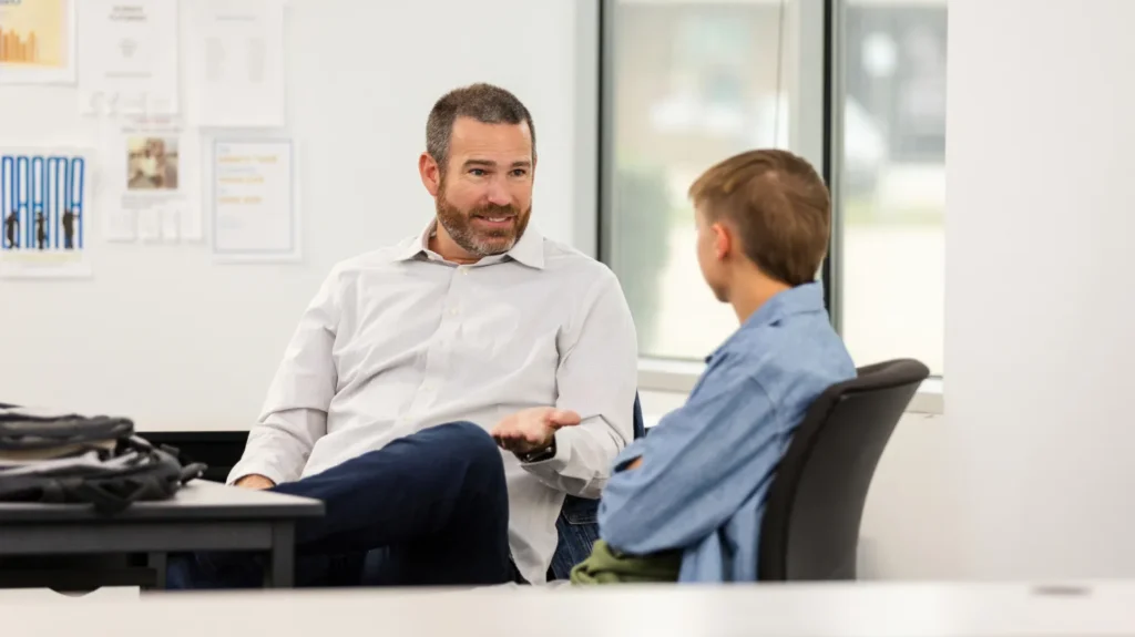 Click for Edutopia article. Picture of a principal speaking to a student.